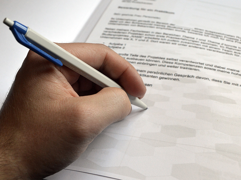 Hand holding a pen and writing on a form
